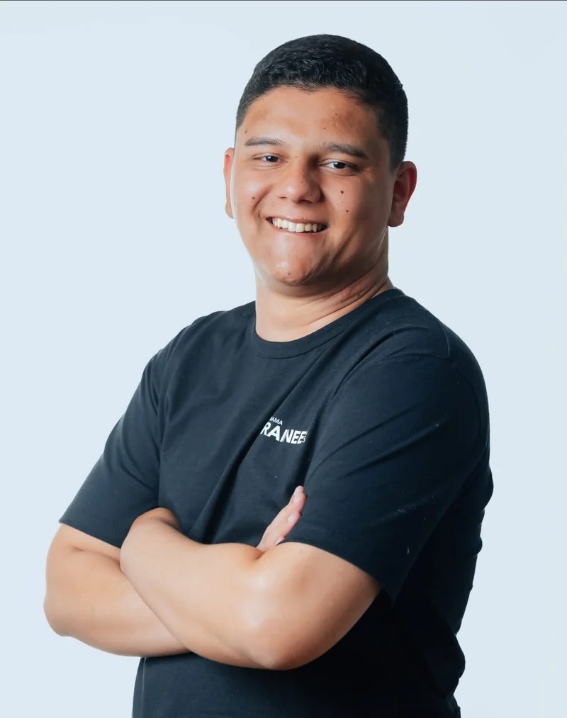 Retrato de Eduardo Mendes sorrindo, com camiseta preta, sobre fundo claro